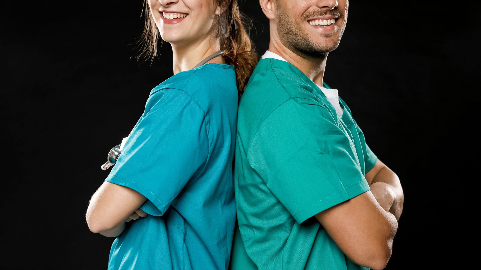 A man and woman in scrub suits standing together, wearing the standard scrubs uniform