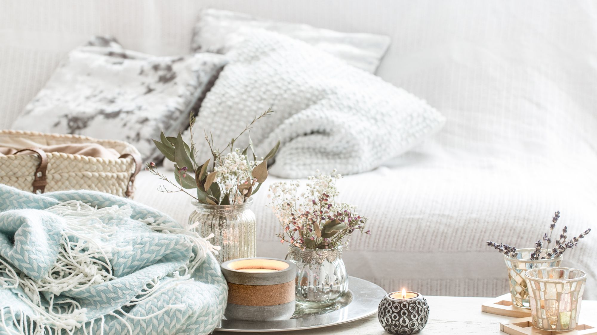 Elegant white couch adorned with a blue blanket and candles, featuring thickest tog duvet and best home textiles.