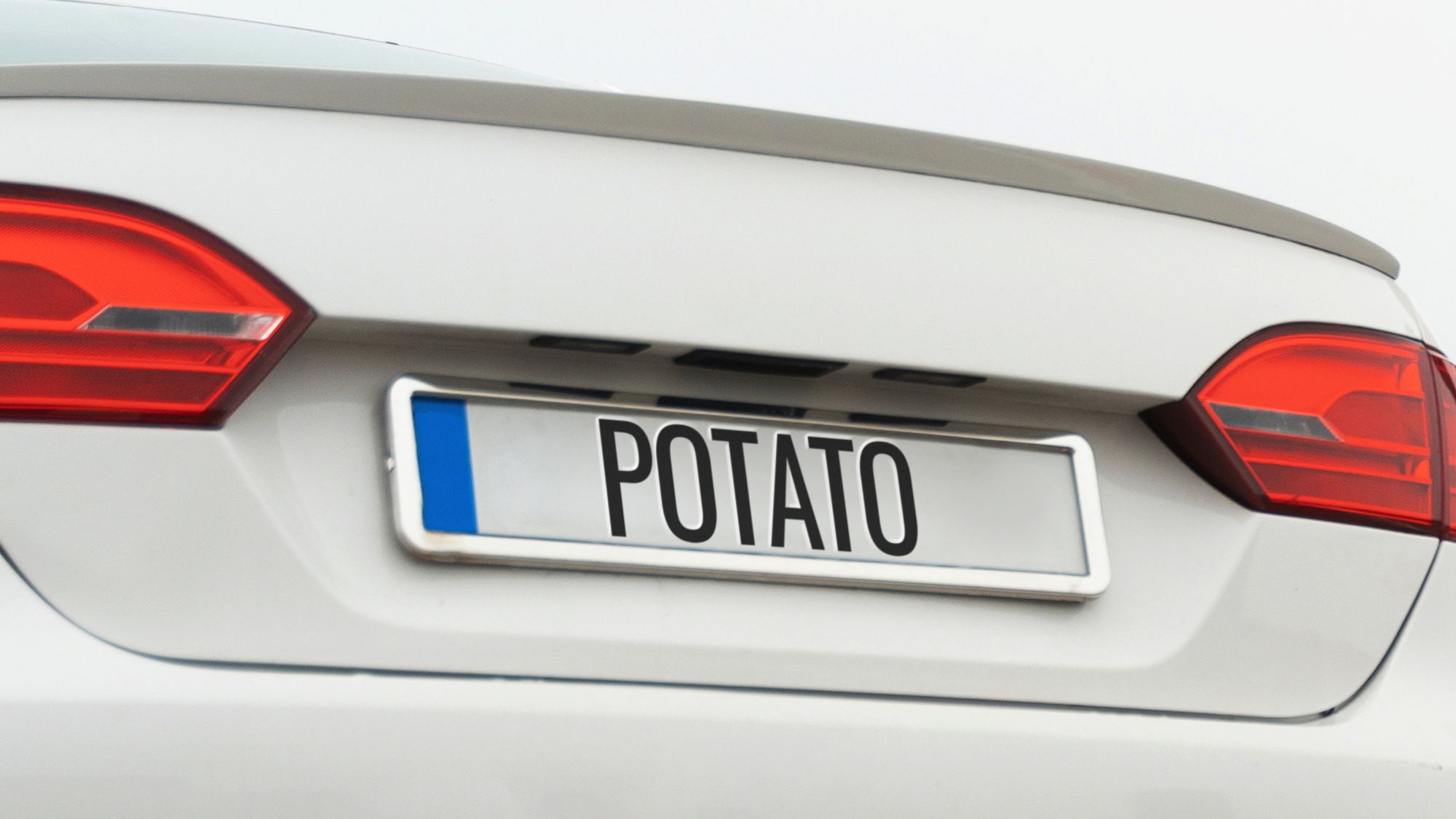 White car with 'potato' on back, displaying number plate sticky pads. Learn about automatic number plate recognition.